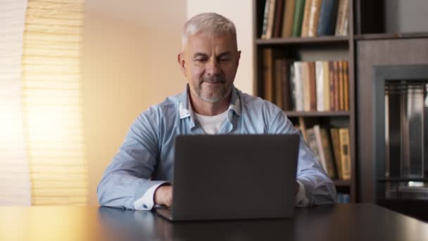 Uomo maturo navigare in internet sul computer portatile, seduto al gabinetto a casa — Video Stock