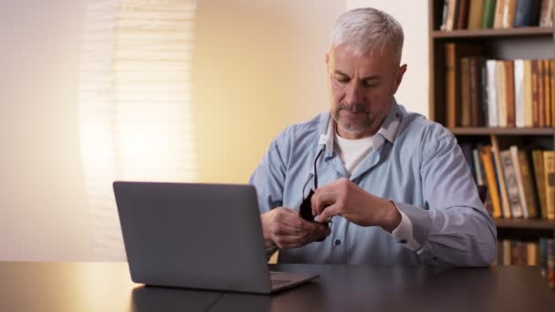 Uomo maturo pulire e mettere gli occhiali e lavorare con il computer portatile a casa ufficio — Video Stock