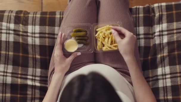 Ciężarna kobieta jedząca frytki i ogórki, ciesząca się niezdrowym jedzeniem w domu, widok z góry, zwolnione tempo — Wideo stockowe
