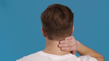 Adamın iltihaplı boynuna, mavi stüdyo geçmişine, yavaş çekimde masaj yaptığı arka plan görüntüsü.