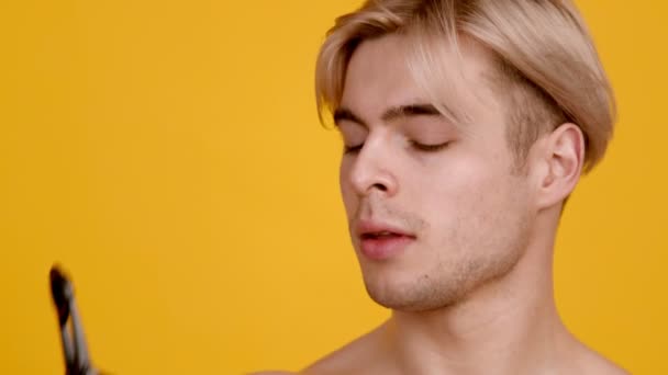 Gepassioneerd naakt gespierde man drinkwater, druppels vallen op gezicht, close-up, oranje achtergrond, slow motion — Stockvideo