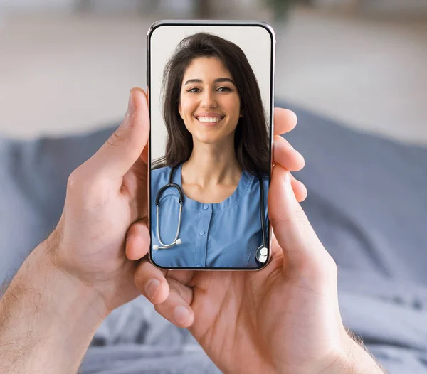 Telemedicina. Ritratto di sorridente medico femminile sullo schermo dello smartphone nelle mani maschili — Foto Stock