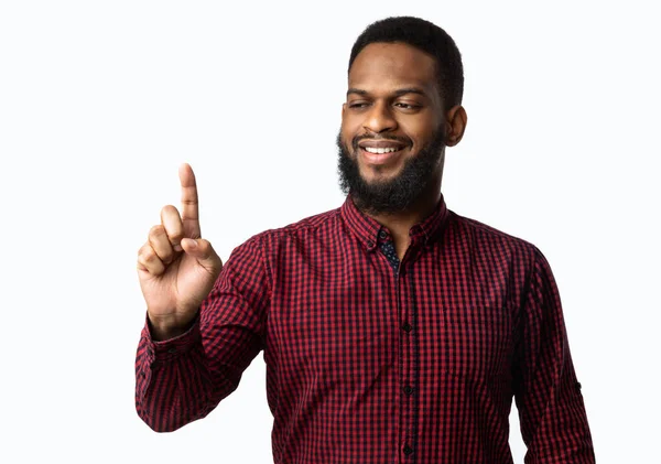 Schwarzer Kerl hält unsichtbares Objekt auf Finger über weißem Hintergrund — Stockfoto