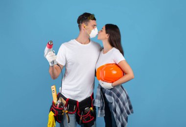 İnşaat aletleri olan romantik adam ve kadın dairelerini tamir ederken öpüşüyorlar.