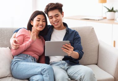 Tabletli Asyalı çift evde video görüşmesi yapıyor.