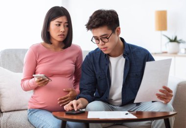 Mutsuz Çinli eşler, evdeki koltukta oturan faturaları hesaplıyorlar.