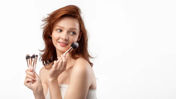 Rothaarige Mädchen halten kosmetische Make-up-Pinsel über weißem Hintergrund — Stockfoto