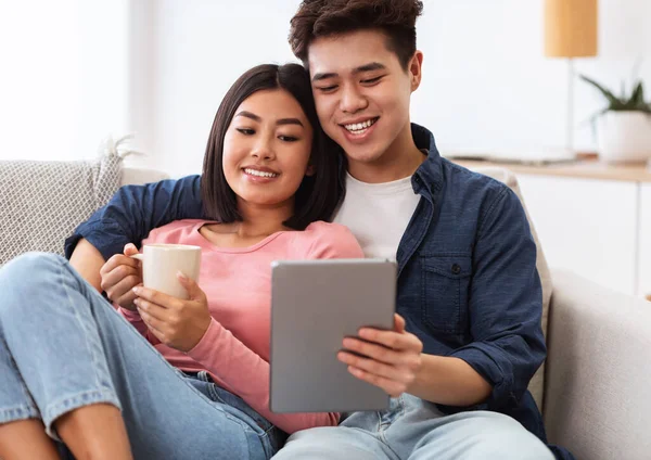 Casal asiático usando tablet computador assistindo filme on-line em casa — Fotografia de Stock