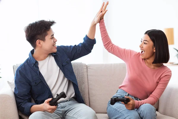 Casal japonês jogando jogos de computador dando alta cinco em casa — Fotografia de Stock