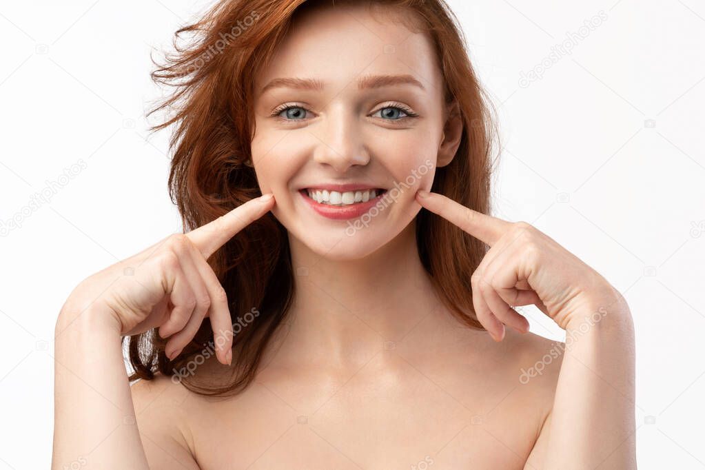 Red-Haired Young Lady Touching Dimples In Cheeks Smiling, White Background