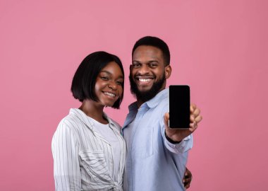 Şu uygulamayı kontrol et. Romantik siyah çift pembe arka planda boş ekranlı akıllı telefon gösteriyor, tasarım için model.