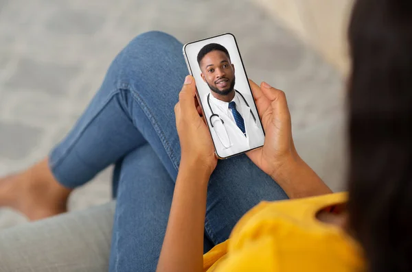 Concept de télémédecine. Dame noire méconnaissable utilisant un téléphone intelligent, faisant une vidéoconférence avec le médecin — Photo