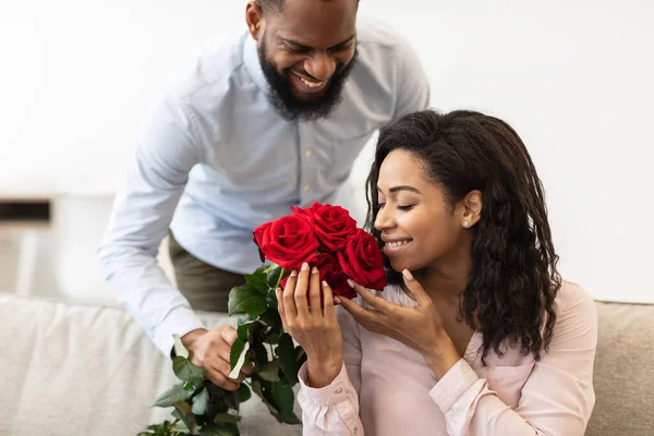 Молодой черный мужчина дарит женщине красные цветы — стоковое фото