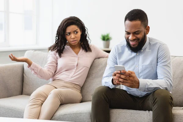 Boos zwarte vrouw op zoek naar vriendje, man met behulp van telefoon — Stockfoto