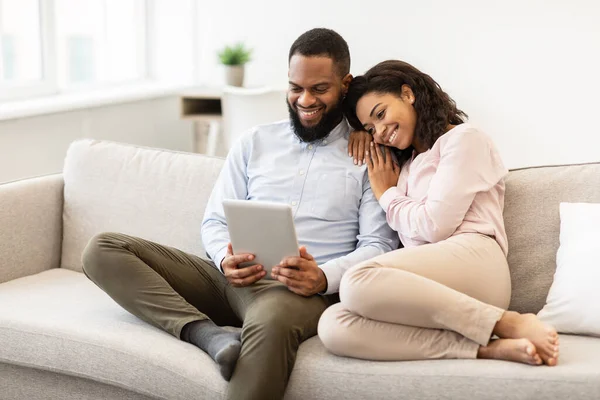 Afrikanisches Paar sitzt auf Couch und benutzt Tablet — Stockfoto