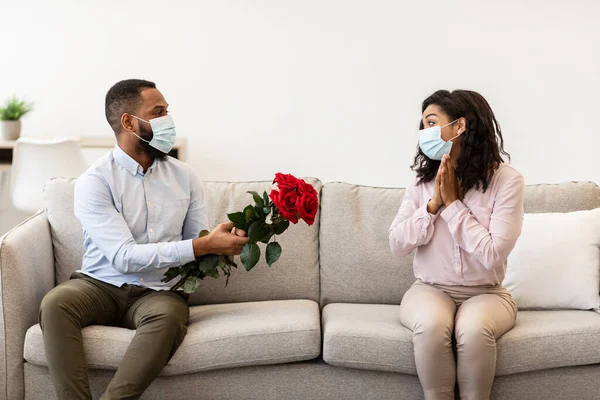 Hombre negro con máscara médica dando rosas a su mujer — Foto de Stock