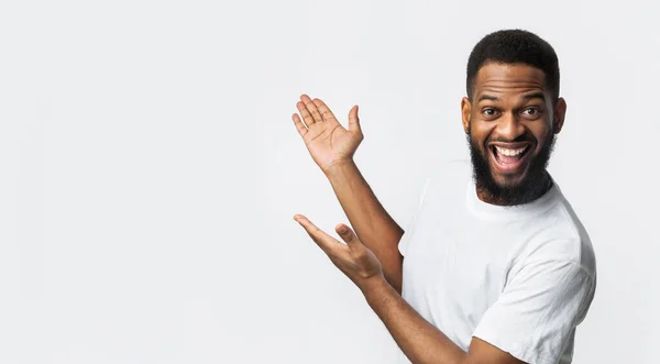 Joyful Black Man Gesturing Mostrando espacio libre de pie en el estudio — Foto de Stock