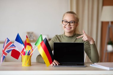 Mutlu liseli kız boş laptop ekranını gösteriyor.