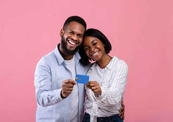 Portrait de joyeux couple afro-américain avec carte de crédit étreignant et regardant la caméra sur fond rose — Photo
