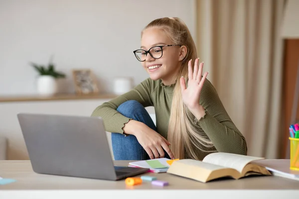 Pretty school girl waving at laptop screen at home — Stock Photo, Image