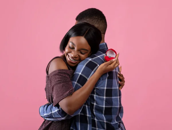 Señora negra con anillo de compromiso abrazando a su futuro marido, diciendo SÍ a su propuesta de matrimonio sobre fondo rosa — Foto de Stock