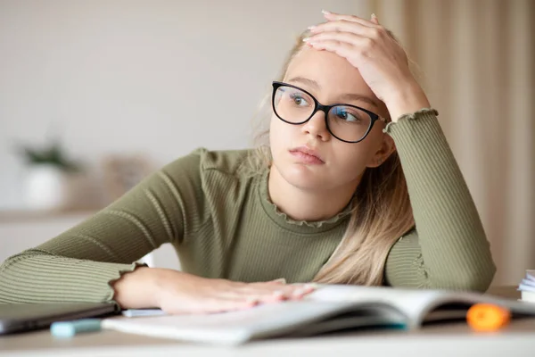 Fatigado adolescente menina sentado em casa com livro, fazendo lição de casa — Fotografia de Stock