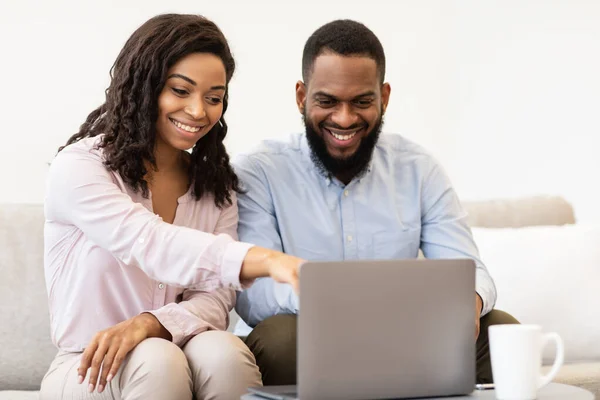 Couple afro-américain assis sur le canapé, en utilisant un ordinateur portable — Photo