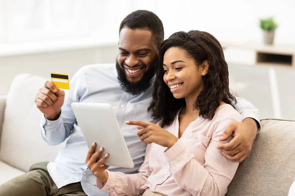 Black couple using tablet and debit credit card at home