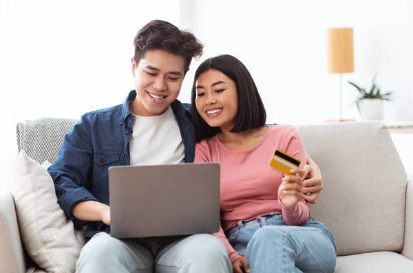 Casal japonês compras on-line usando laptop e cartão de crédito interior — Fotografia de Stock
