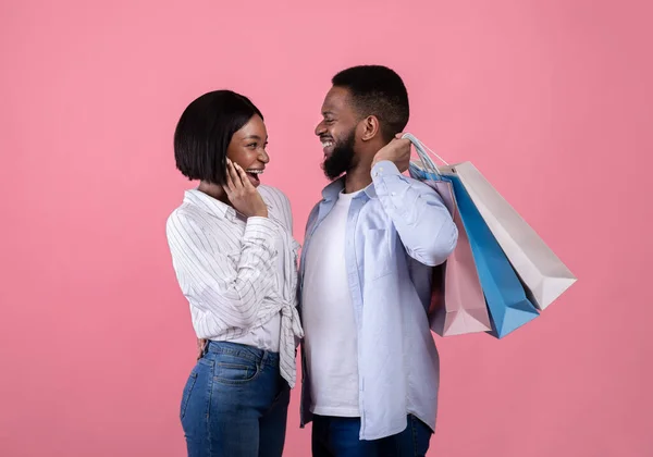 Heureux jeune homme noir avec son amoureux tenant des sacs à provisions, l'achat de cadeaux pour les amoureux jour sur fond rose — Photo