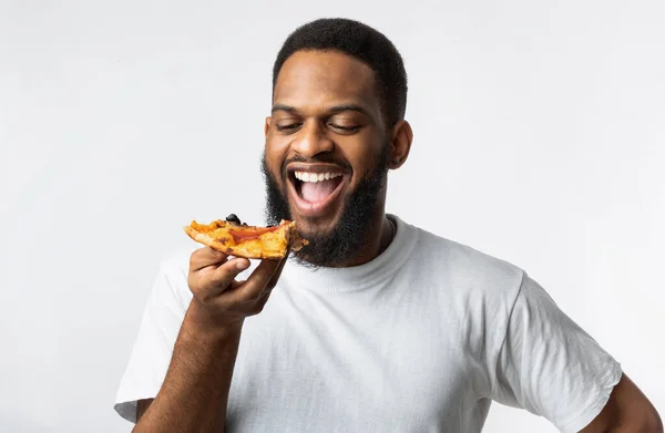 Alegre africana millennial cara comer pizza fatia sobre fundo branco — Fotografia de Stock
