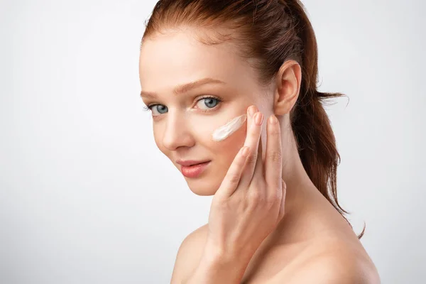 Ingwer-Haired Girl Applying Gesichtscreme Care For Skin In Studio — Stockfoto