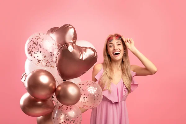 Belle dame joyeuse avec des ballons de vacances s'amuser sur son anniversaire fête sur fond de studio rose — Photo