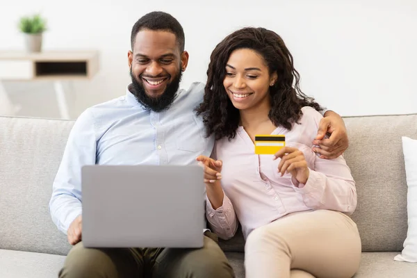 Casal preto usando laptop e cartão de crédito de débito em casa — Fotografia de Stock