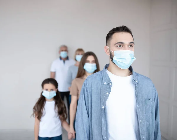 Young Caucasian guy in face mask waiting in line for coronavirus vaccination at health centre, copy space — Stock Photo, Image