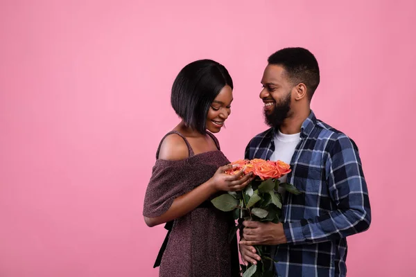 Liefdevolle Afro-Amerikaanse man presenteren zijn geliefde met bos rozen op Valentijnsdag over roze achtergrond — Stockfoto