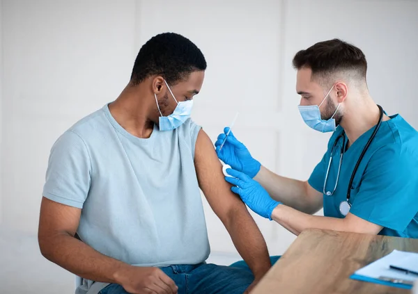 Médico o enfermero que administra la vacuna contra el coronavirus a un paciente afroamericano en la clínica —  Fotos de Stock