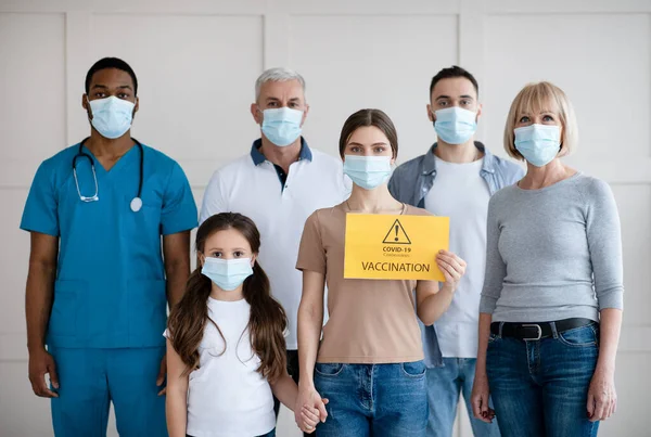 Portrait of black doctor and diverse patients with COVID-19 VACCINATION sign looking at camera and posing in clinic — Stock Photo, Image