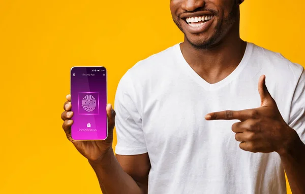 Fekete ember mutat a mobiltelefon ujjlenyomat szkenner, sárga háttér — Stock Fotó