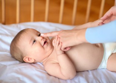 Sevimli bebek annesine bakıyor, tahta bebek yatağında yatıyor.