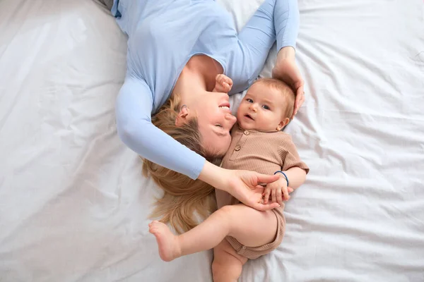 Sevimli erkek bebek ve sevgi dolu sarışın anne yatakta yatıyor. — Stok fotoğraf