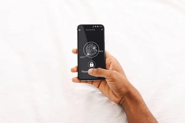 Невідомий чорний чоловік сканує відбиток пальця на телефоні над білим тлом — стокове фото