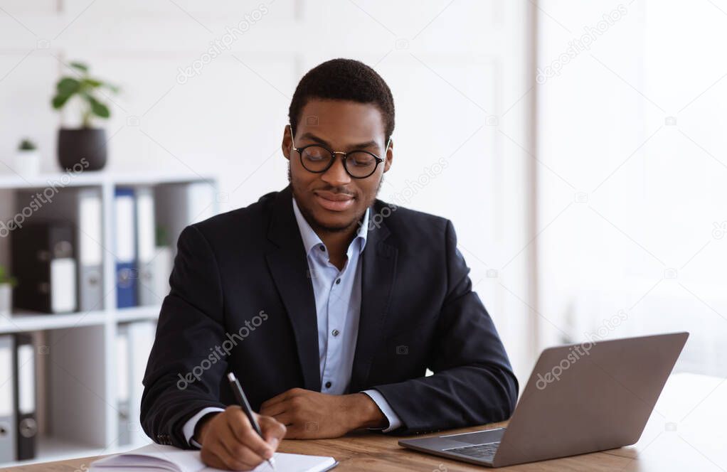 Enthusiastic black businessman planning his day in office