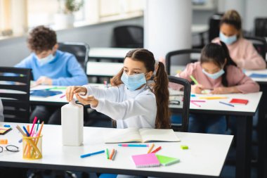 Elinde antibakteriyel dezenfektan kullanan küçük bir kız.