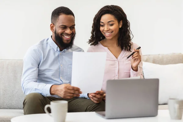 Alegre pareja negra leyendo documentos en casa, verificando acuerdo — Foto de Stock