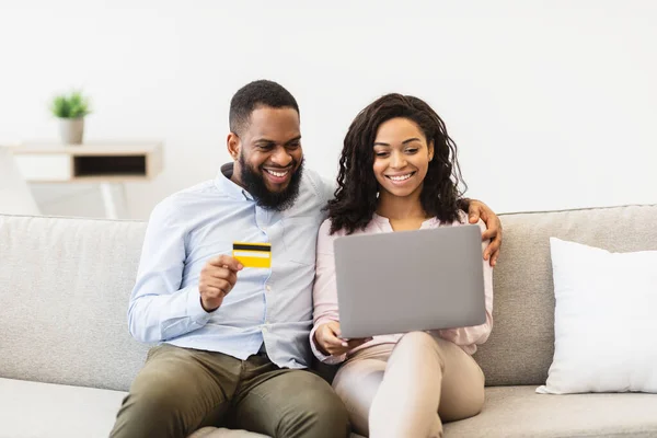Black couple using computer and debit credit card at home