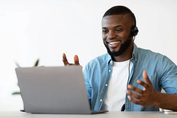Video Conference. Cheerful african american man in headset making web call on laptop