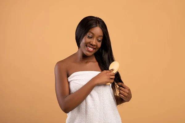 Hübsche schwarze Frau bürstet ihr langes schönes Haar — Stockfoto