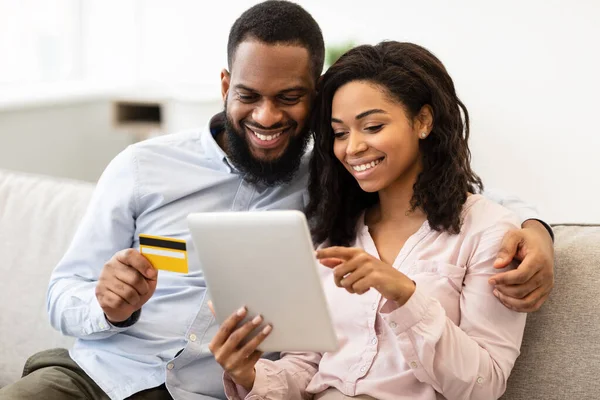 Pareja negra usando tableta y tarjeta de crédito de débito en casa —  Fotos de Stock