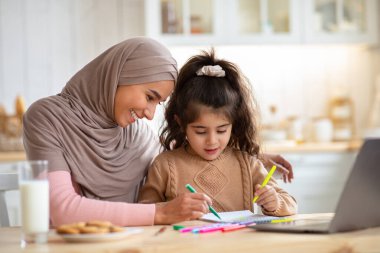Mutfaktaki küçük kızıyla tesettürde çizim yapan Müslüman Anne